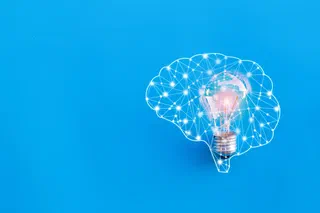 A lightbulb representing an idea surrounded by a network in the form of a brain.
